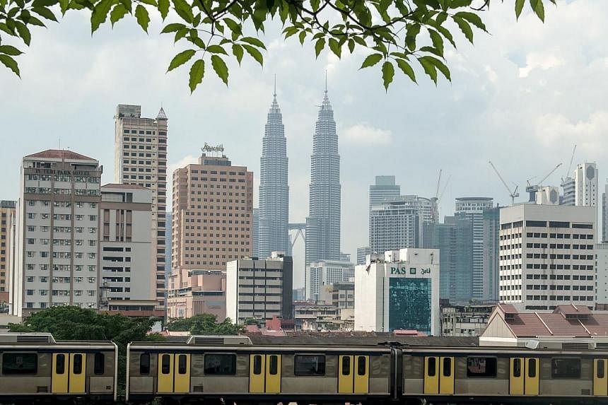 A Light Rail Transit (LRT) train travels along the tracks as Malaysia's iconic Petronas Twin Towers loom in the backgrond in downtown Kuala Lumpur on May 29, 2014.&nbsp;Malaysia’s economy is expected to expand 5.4 per ent this year, picking up from