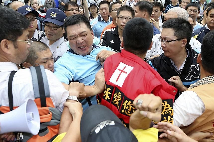 Pro-democracy activists (in red and orange vests) scuffle with police officers (in black and blue shirts) as Mr Zhang Zhijun, director of China's Taiwan Affairs Office, arrives in Kaohsiung, southern Taiwan, on June 27, 2014. -- PHOTO: REUTERS
