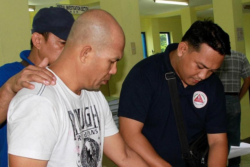 This handout photo taken on June 11, 2014 and released by the Philippine National Police shows senior Philippine Islamic militant Khair Mundos (front L) being fingerprinted by Philippine police after he was arrested in Manila following a manhunt last