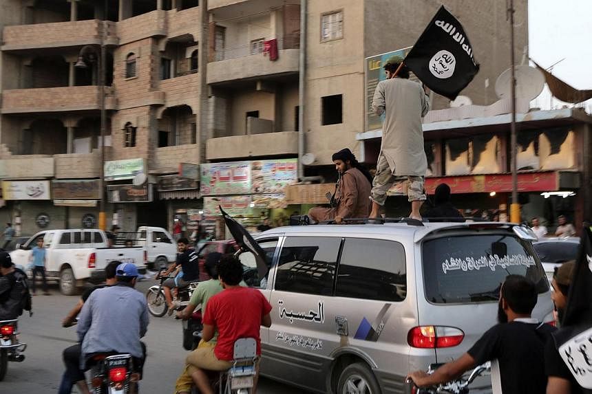 Members loyal to the Islamic State in Iraq and the Levant (ISIL) wave ISIL flags as they drive around Raqqa on June 29, 2014. -- PHOTO: REUTERS