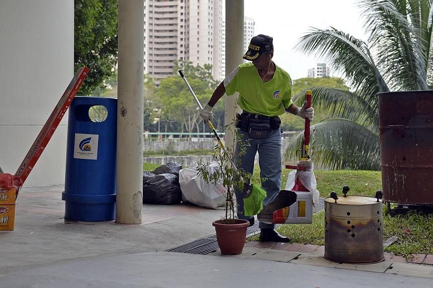 A cleaner sweeping and clearing rubbish at the void deck of a HDB flat at Bukit Panjang. -- PHOTO: ST FILE&nbsp;