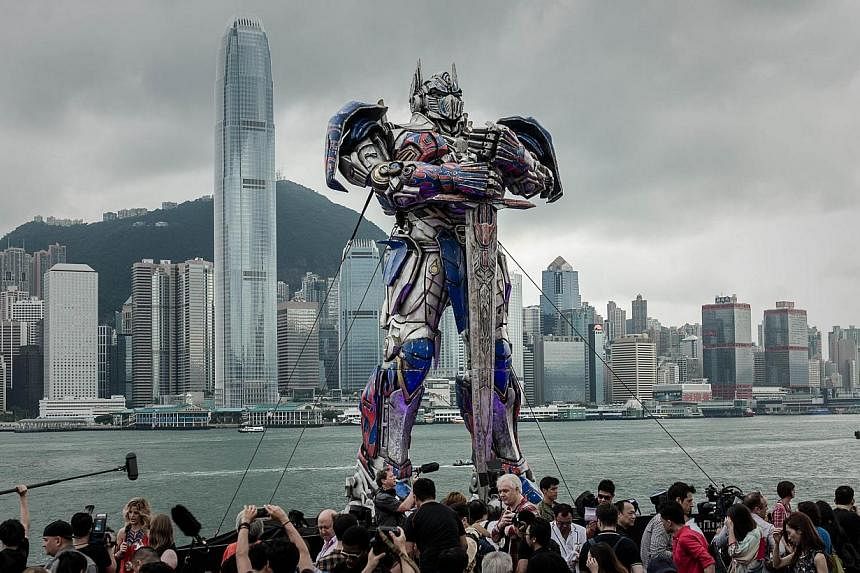 A 20 foot-tall Optimus Prime figure is surrounded by journalists before the world premiere of Hollywood movie Transformers 4 in Hong Kong on June 19, 2014.&nbsp;Transformers: Age Of Extinction, the fourth in the series of films about form-changing Au