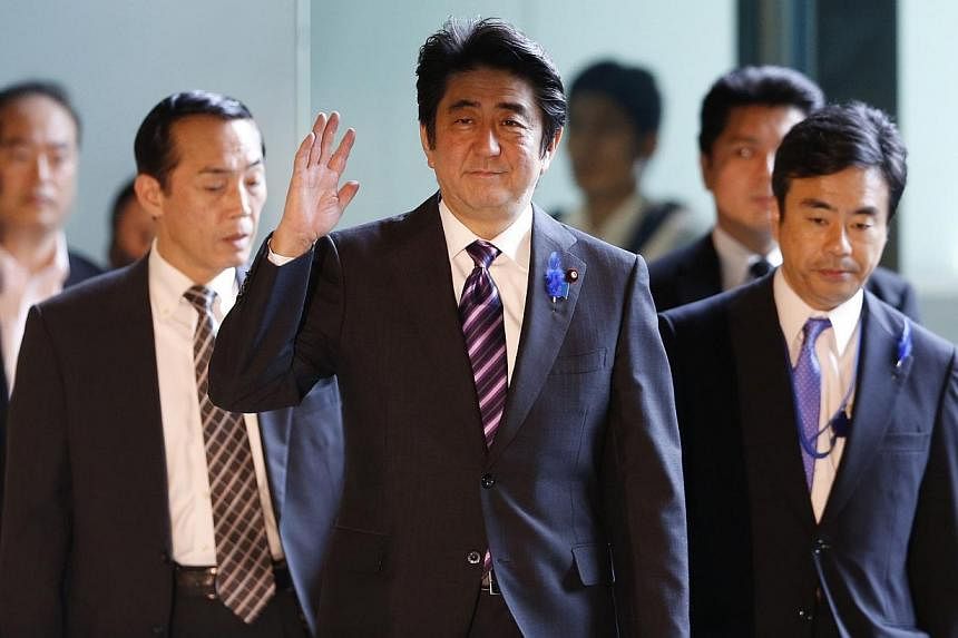 Japan's Prime Minister Shinzo Abe (centre) waves upon his arrival at his official residence in Tokyo July 1, 2014.&nbsp;Japan on Tuesday loosened restrictions on its powerful military, allowing it to go into battle in defence of allies, in a major an