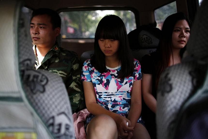A female teacher and an instructor who is an ex-soldier, escort a girl in a car as they take her to the Qide Education Center at the request of her parents in Beijing on May 22, 2014. &nbsp;-- PHOTO: REUTERS