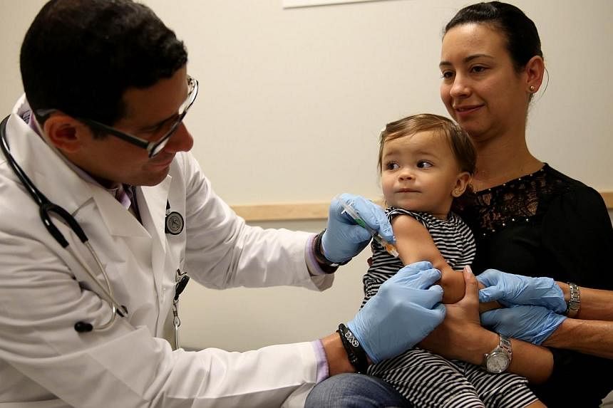 &nbsp;Daniela Chavarriaga holds her daughter, Emma Chavarriaga, as paediatrician Jose Rosa-Olivares administers a measles vaccination during a visit to the Miami Children's Hospital on June 2, 2014 in Miami, Florida. -- PHOTO: AFP&nbsp;