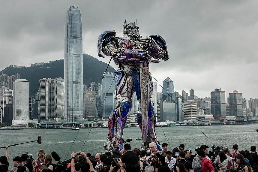 A 20 foot-tall Optimus Prime figure is surrounded by journalists before the world premiere of Hollywood movie Transformers 4 in Hong Kong on June 19, 2014.&nbsp;The fourth installment of the smash hit Transformers franchise topped the North American 