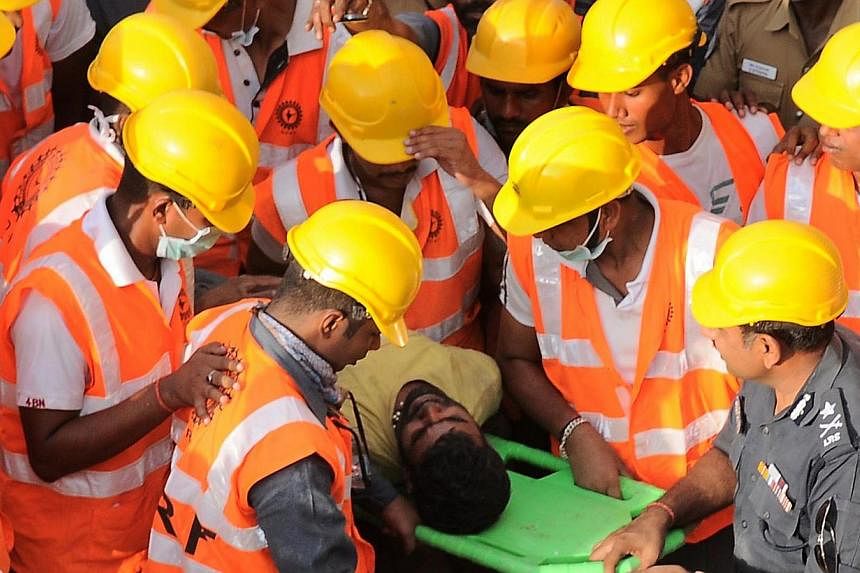 Rescue workers surrounding 23 year-old labourer from Orissa state, Prakesh, as he is carried out alive from the rubble on a stretcher, 72 hours after the collapse of the multi-storied building in Porur Town, near Chennai on July 1, 2014. Emergency wo