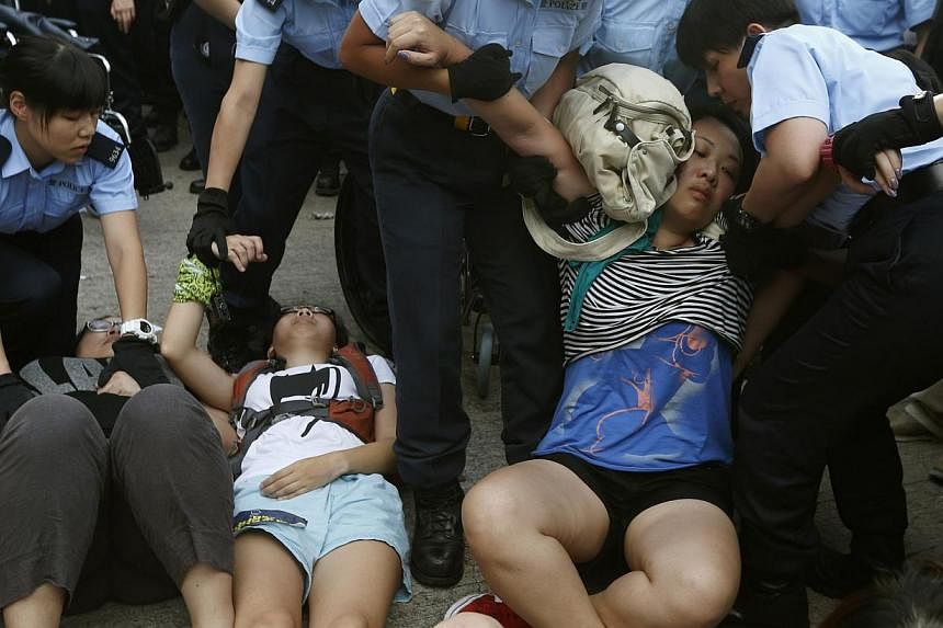 A protester is dragged away by policewomen on a street at Hong Kong's financial Central district on July 2, 2014, after an overnight sit-in with fellow protesters. Hundreds of police forcibly removed kicking and screaming protesters from the Central 