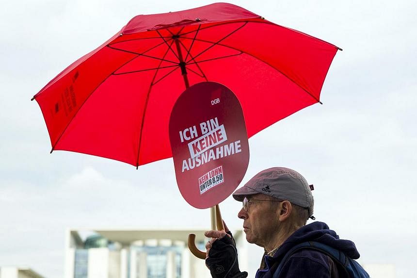A man holds a placard during a labour union protest in support of a nationwide minimum wage in front of the Chancellery in Berlin on June 30, 2014. -- PHOTO: REUTERS