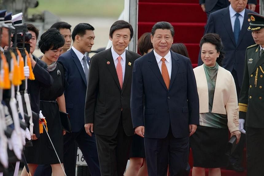 China's President Xi Jinping (centre) and his wife Peng Liyuan (second, right) are welcomed after disembarking from their aircraft upon arrival at Seoul Air Base on July 3, 2014. Mr Xi arrived in Seoul on Thursday, July 3, 2014, for a state visit see