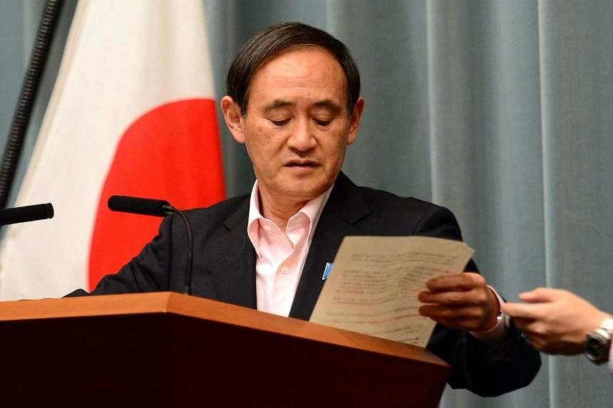Japan's Chief Cabinet Secretary Yoshihide Suga receives a paper from an official at a press conference at the prime minister's official residernce in Tokyo on May 29, 2014.&nbsp;Japan has decided to lift part of its sanctions against North Korea, pub