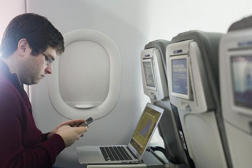 A man uses his mobile phone on a flight out of John F. Kennedy International Airport in New York in 2013. Airlines with direct flights to the United States have been told to tighten screening of mobile phones and shoes in response to intelligence rep