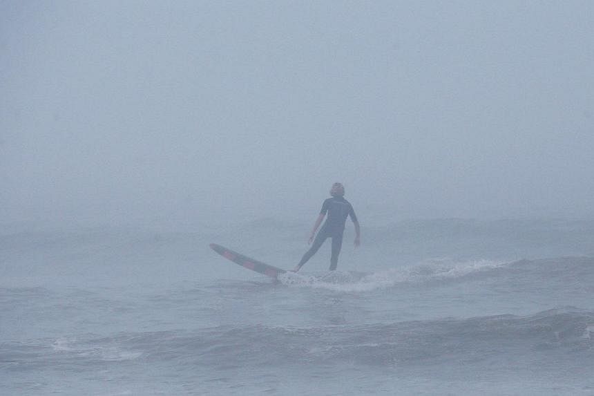 A man surfs in the fog as strong winds and heavy surf from Hurricane Arthur begin to roll in, on July 3, 2014 in Nags Head, North Carolina. Hurricane warning has been issued for North Carolina's Outer Banks due to approaching Hurricane Arthur. -- PHO
