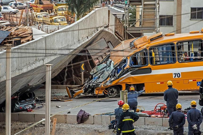 Firefighters and policemen work at the site where several vehicles were crushed by a viaduct that collapsed in Belo Horizonte, Brazil, on July 3, 2014. The collapse killed&nbsp;at least two people, emergency officials said.&nbsp;-- PHOTO: AFP