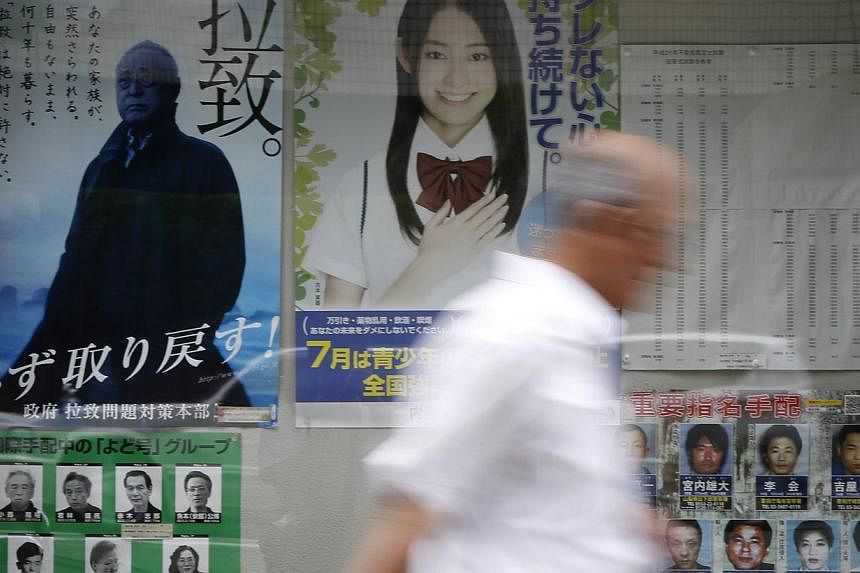 A man walks past a campaign poster on Japan's abduction issue (left) on a street in Tokyo on July 3, 2014. Japan decided on Thursday to ease some sanctions on North Korea in return for its reopening of a probe into the fate of Japanese citizens abduc
