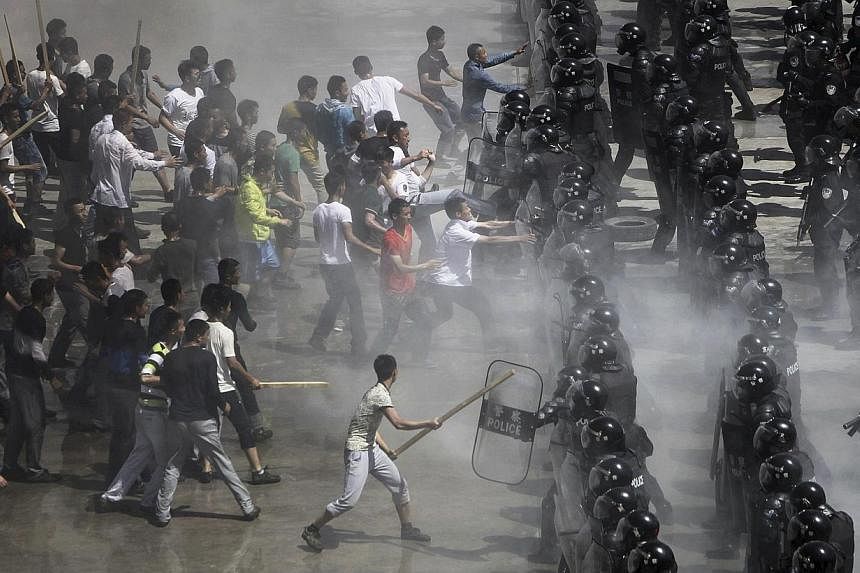 Mock rioters (L) clash with riot policemen during an anti-terrorist drill in Beijing on May 29, 2014. Over 2,800 people from Beijing police forces attend this drill as China starts to launch a year-long nationwide anti-terrorism operation after fatal