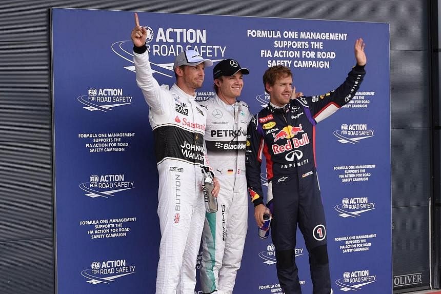 (From left) McLaren Mercedes' British driver Jenson Button, Mercedes-AMG's German driver Nico Rosberg and Red Bull Racing's German driver Sebastian Vettel celebrate in the parc ferme after the qualifying session at the Silverstone circuit in Silverst