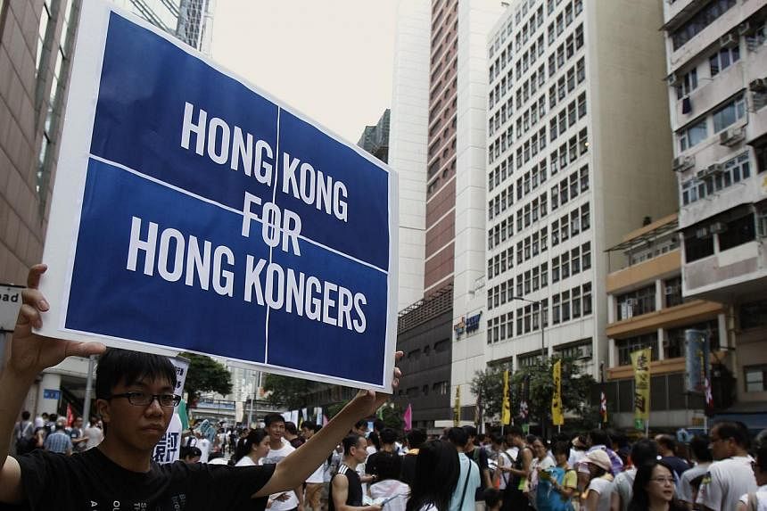 A protester carries a placard during a mass protest demanding universal suffrage in Hong Kong on July 1, 2014. -- PHOTO: REUTERS