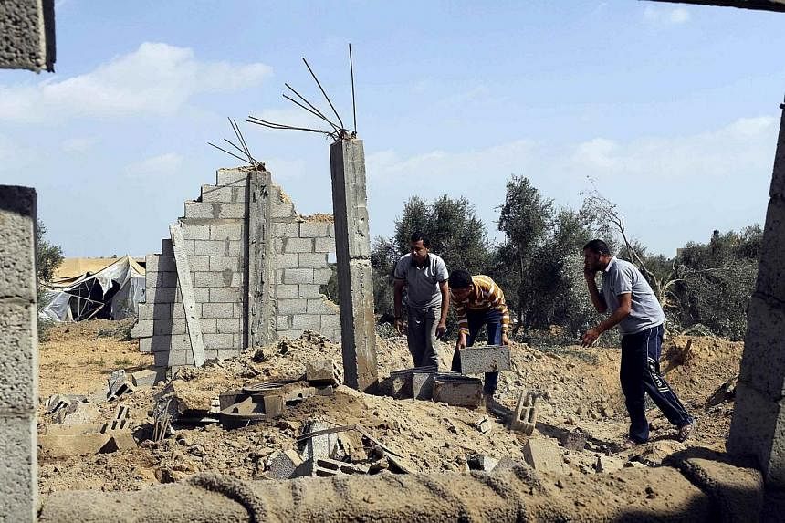 Palestinians inspect what police said is the aftermath of an Israeli air strike in Khan Younis in the southern Gaza Strip July 6, 2014.&nbsp;Israeli aircraft attacked 10 sites used by Palestinian militants in the Gaza Strip on Sunday in response to p