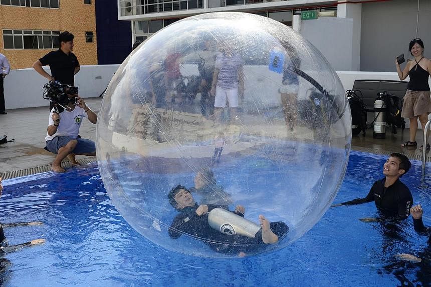 Candidates testing a water balloon at a pool in Geylang last month. They are vying to be the first Singaporean to be launched in a helium stratospheric balloon craft into near-space, more than 20km above sea level, next year.