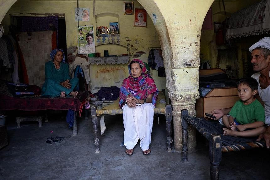 In this photograph taken on May 5, 2014 Assamese villager Meera Deka (centre) sits next to her father-in-law, Ranbeer Singh (right) and mother-in-law, Sajini Devi (left) during an interview with AFP at her home in Hissar district of the northern stat