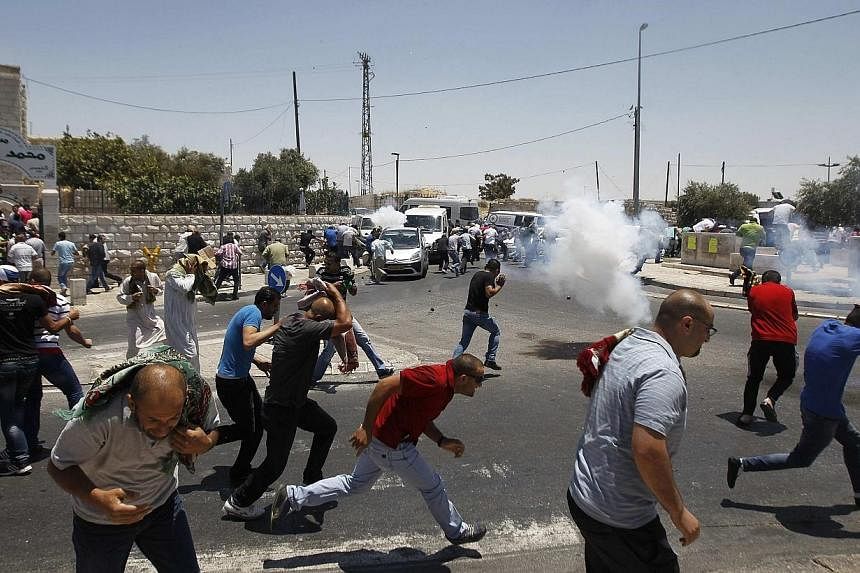 Palestinian protesters run away from tear gas fired by Israeli soldiers during clashes after Friday payers in the Arab east Jerusalem neighbourhood of Ras al-Amud on July 4, 2014.&nbsp;Clashes sparked by the abduction and murder of a Palestinian teen