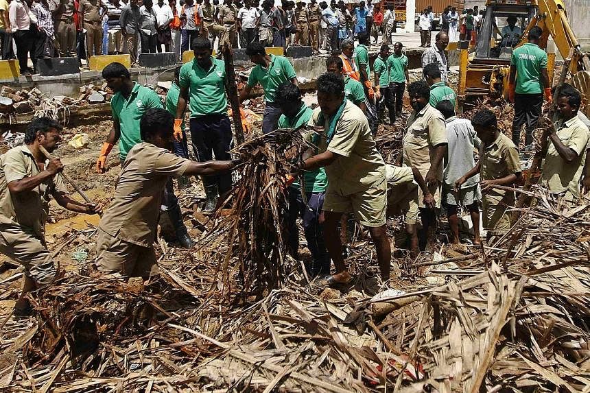 Rescue workers clear the debris from the site of a collapsed compound wall of a warehouse on the outskirts of the southern Indian city of Chennai on July 6, 2014.&nbsp;A wall collapsed on Sunday in southern India killing 11 people including a child, 
