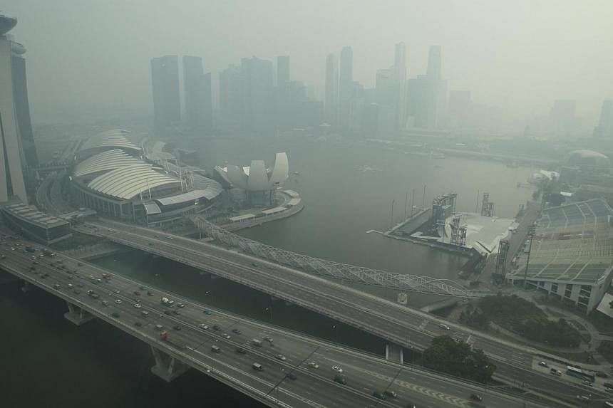 A file picture from June 17, 2013, showing the Marina Bay area shrouded in haze.&nbsp;An ambitious Bill to fight transboundary haze here has proposed fining errant firms up to $2 million, nearly seven times what it originally suggested. -- ST PHOTO: 