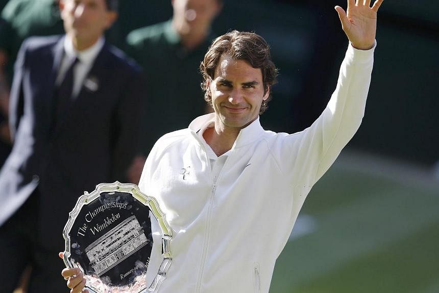Roger Federer of Switzerland waves while holding the runner-up's trophy after being defeated by Novak Djokovic of Serbia in their men's singles finals tennis match on Centre Court at the Wimbledon Tennis Championships in London on July 6, 2014.&nbsp;