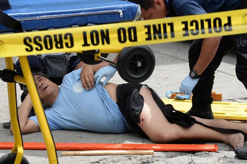 Philippine emergency personnel attend to a victim of robbery along a street in the financial district of Manila on July 7, 2014. &nbsp;According to a witness quoted by media reports, the victim, a company messenger, was walking towards a local bank w