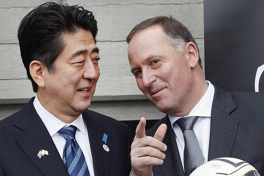 Japan's Prime Minister Shinzo Abe (left) speaks with his New Zealand counterpart John Key, as he holds a rugby ball at Villa Maria winery in Auckland on July 7, 2014.&nbsp;The thorny issue of whaling dominated Japanese Premier Shinzo Abe’s whistles