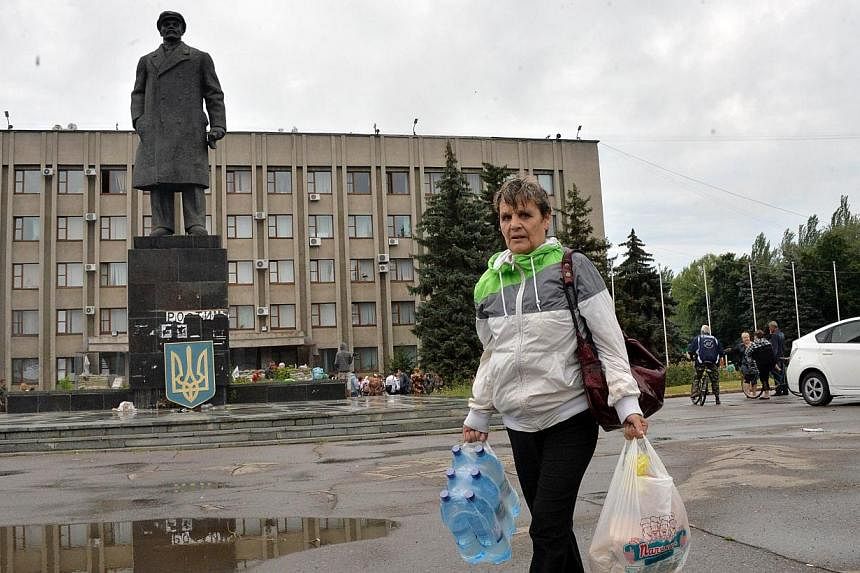 &nbsp; &nbsp;A resident of the eastern Ukrainian city of Slavyansk carries water and bread given out by Emergency Ministry employees at the city hall as she walks in the street on July 6, 2014. -- PHOTO: AFP&nbsp;