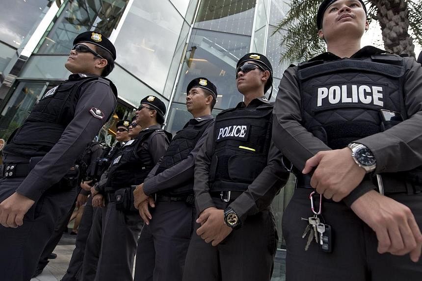 Thai policemen stand guard during a demonstration by an anti-coup protester at a shopping mall in Bangkok on June 22, 2014.&nbsp;Thailand's military government said on Monday peace in the Muslim-dominated south was an "urgent national priority" for t