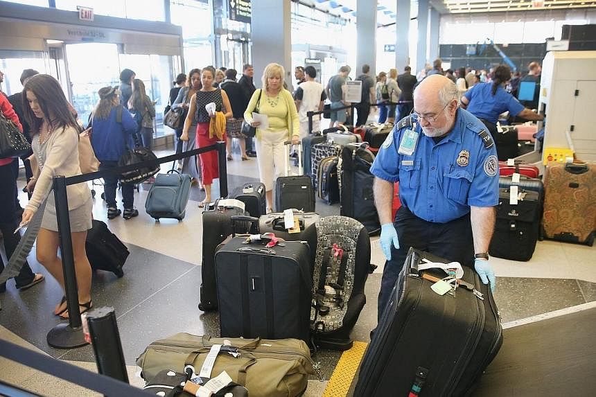 A Transportation Security Administration (TSA) agent checks luggage as passengers arrive for flights at O'Hare International Airport May 23, 2014 in Chicago, Illinois. The TSA will not allow cellphones or other electronic devices on US-bound planes a