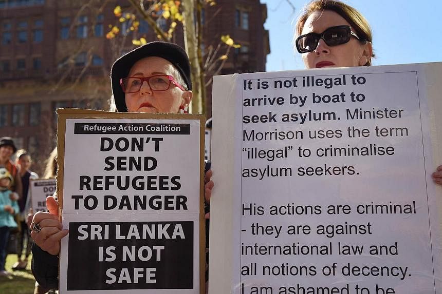 Two people hold placards at a rally protesting the Australian government's treatment of Sri Lankam asylum-seekers in Sydney on July 7, 2014. -- PHOTO: AFP