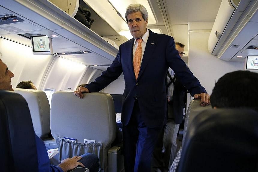US Secretary of State John Kerry greets media representatives flying aboard his plane bound for diplomatic talks in China while flying out of Washington, DC on July 7, 2014.&nbsp;-- PHOTO: AFP