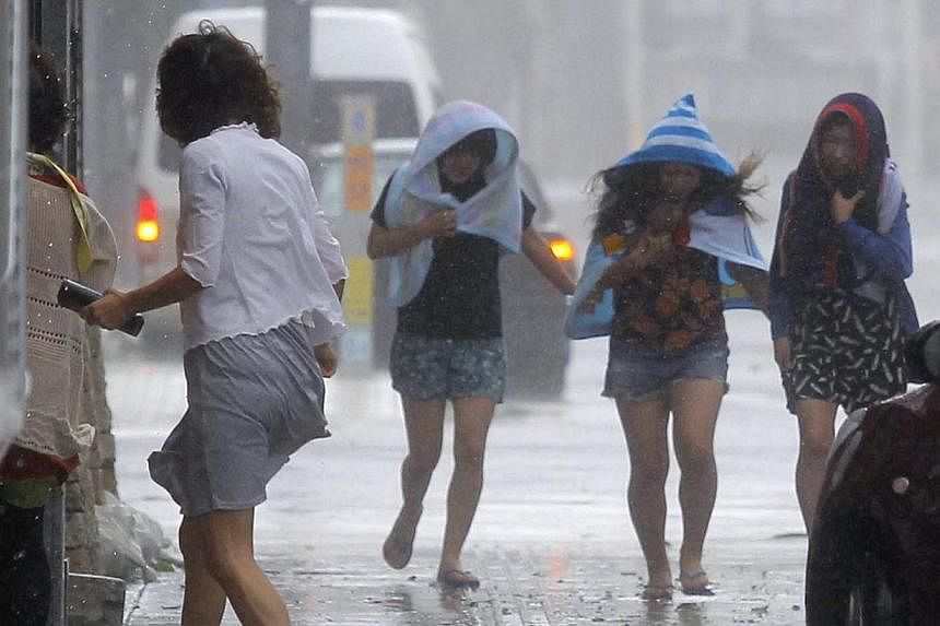 Women walk in strong winds caused by Typhoon Neoguri at Kokusai street, a shopping and amusement district in Naha on Japan's southern island of Okinawa, in this photo taken by Kyodo on July 8, 2014. -- PHOTO: REUTERS