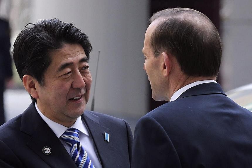 Japanese Prime Minister Shinzo Abe (left) shakes hands with Australia's Prime Minister Tony Abbott at Parliament House in Canberra on July 8, 2014. -- PHOTO: AFP