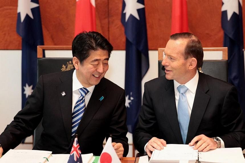 Japanese Prime Minister Shinzo Abe (L) and Australian Prime Minister Tony Abbott smile after signing the Japan-Australia Economic Partnership Agreement and Agreement on the Transfer of Defence Equipment and Technology in the Mural Hall at Parliament 