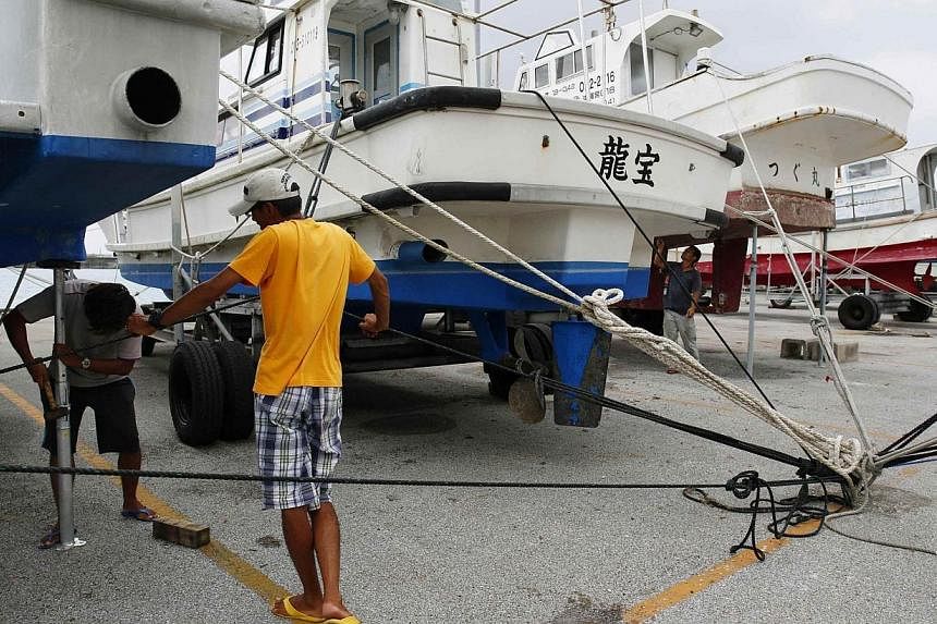 Men secure a fishing boat at a port as super typhoon Neoguri approaches the region, on Japan's southern island of Miyakojima, Okinawa prefecture, in this photo taken by Kyodo on July 7, 2014.&nbsp;Japan was bracing on Tuesday for one of its worst sto