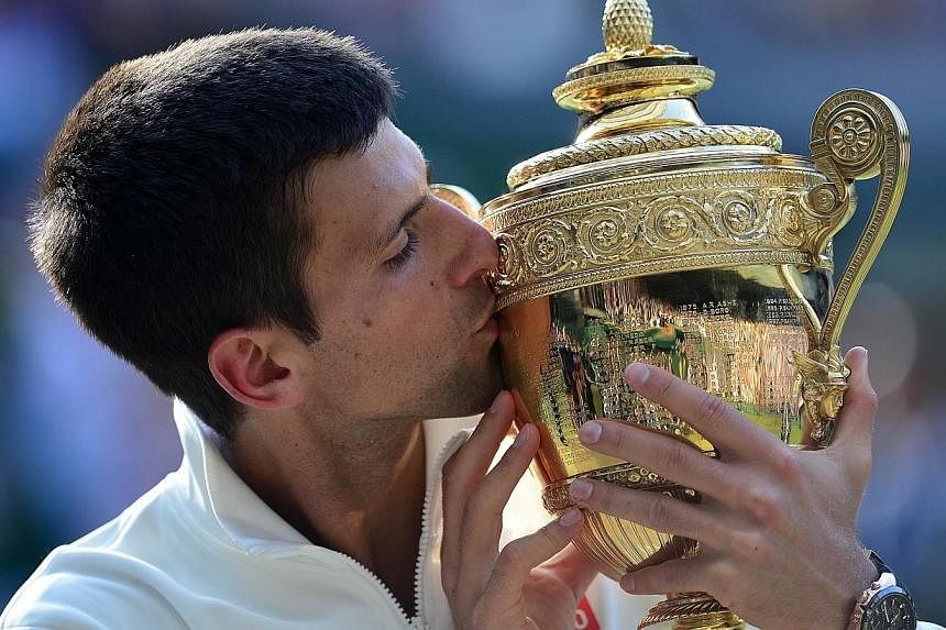 Serbia's Novak Djokovic kisses the winner's trophy after beating Switzerland's Roger Federer in the men's singles final match during the presentation on day thirteen of the 2014 Wimbledon Championships at The All England Tennis Club in Wimbledon, sou