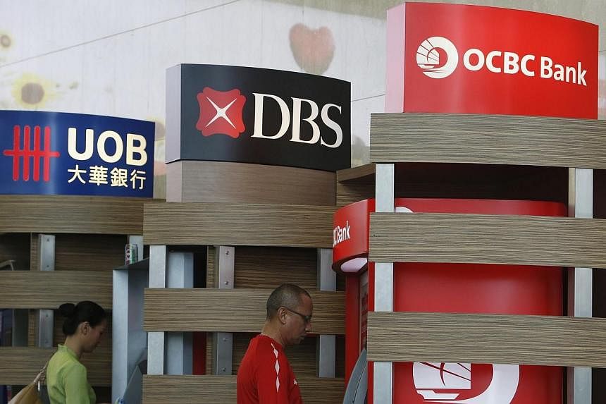 People use Development Bank of Singapore (DBS) and Oversea-Chinese Banking Corp (OCBC) automated teller machines at the airport in Singapore April 30, 2014.&nbsp;Ratings agency Moody's Investors Service has retained its negative outlook on Singapore'