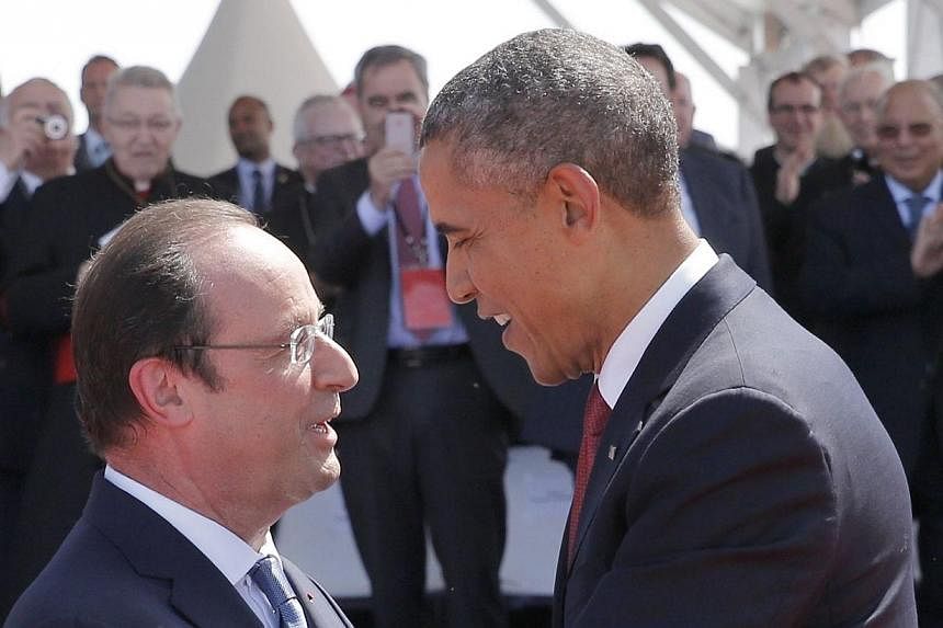 French President Francois Hollande (left) greets US President Barack Obama during an international D-Day commemoration ceremony on the beach of Ouistreham, Normandy, on June 6, 2014, marking the 70th anniversary of the World War II Allied landings in