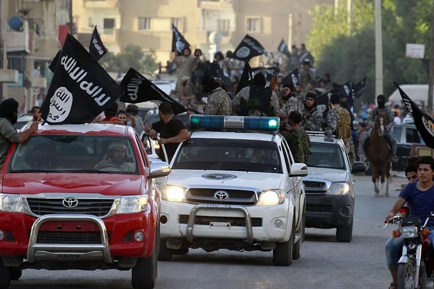 Militant Islamist fighters waving flags, travelling in vehicles as they take part in a military parade along the streets of Syria's northern Raqqa province June 30, 2014. -- PHOTO: REUTERS