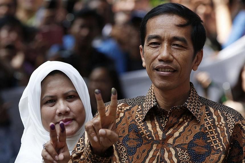 Indonesian presidential candidate Joko "Jokowi" Widodo and his wife Iriana pose for pictures after casting their vote in Jakarta on July 9, 2014. -- PHOTO: REUTERS