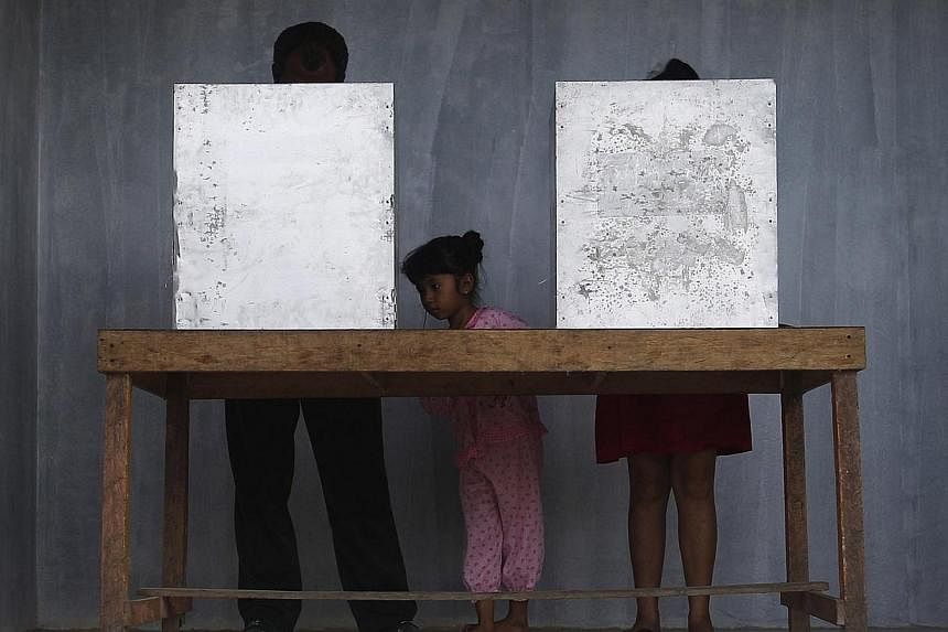 A girl stands between her parents as they vote in Indonesia's presidential election at a polling station in Ranai on the island of Natuna on July 9, 2014. Indonesians began voting on Wednesday in a presidential election that has become a closely foug