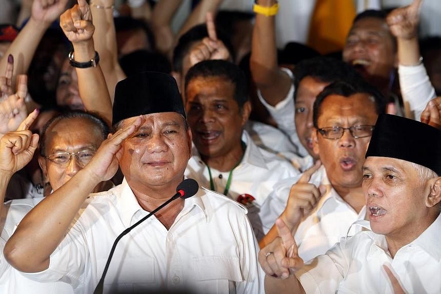 Indonesian presidential candidate Prabowo Subianto (left) gives a salute as his vice presidential running mate Hatta Rajasa (right) and supporters gesture after Prabowo declared victory in Jakarta on July 9, 2014. -- PHOTO: REUTERS