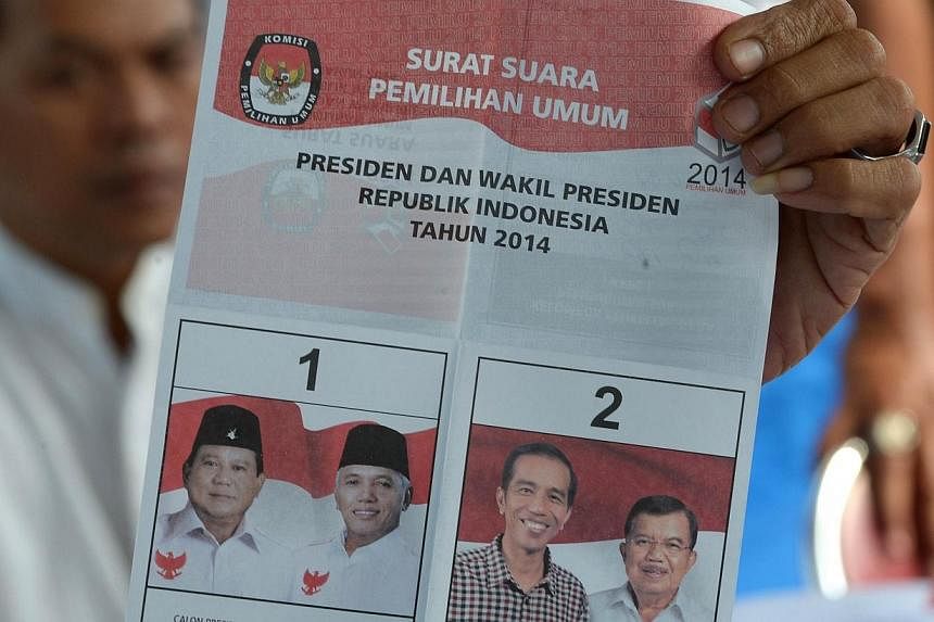A polling centre official holds up a ballot during a tally of Indonesia's presidential election in Jakarta on July 9, 2014.&nbsp;Uncertainty reigned in Indonesia on Wednesday, July 9, 2014, after both presidential candidates claimed victory in a hard