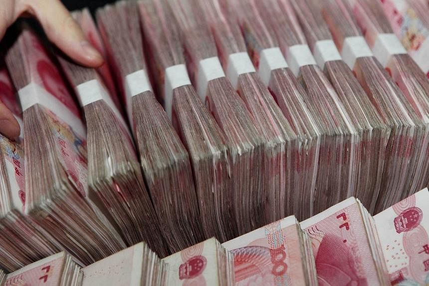 A teller counting notes in a bank in Ganyu county, east China's Jiangsu province on Feb 26, 2014.&nbsp;More companies in Singapore are using yuan to settle their cross-border business transactions, according to a survey by HSBC. -- PHOTO: AFP