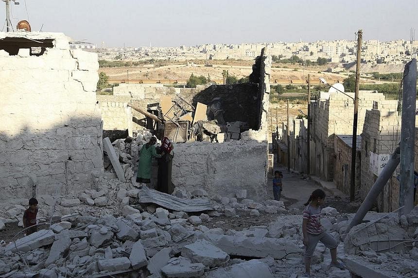 People walk on the debris of collapsed buildings in Sheikh Saeed neighbourhood in Aleppo on July 9, 2014.&nbsp;Twenty members of the Islamic State (IS) were killed in Syrian air force raids on Wednesday, July 9, 2014, against the jihadists' bastion i